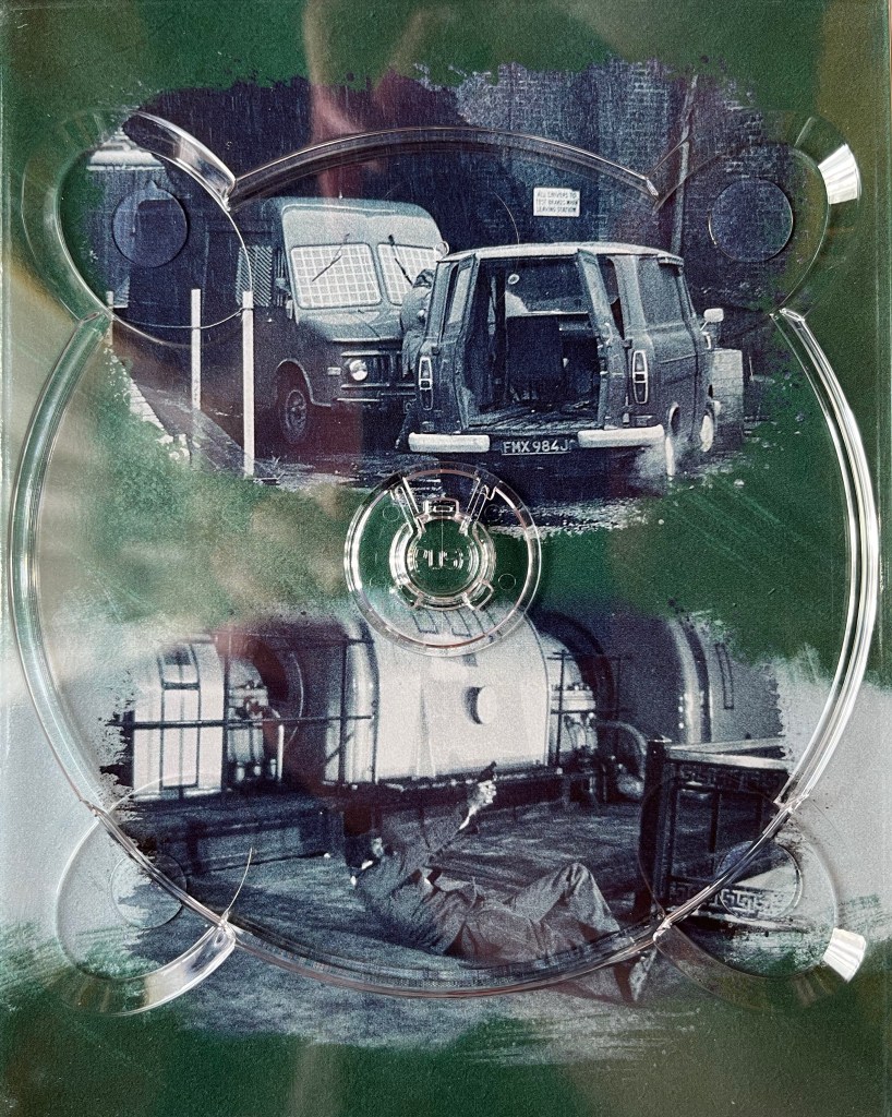 A panel with a green background from the Blu-ray box set for The Sweeney Series 2. It has 2 black and white images, the top one showing a small van with its back doors open as it blocks the path of a larger security van, while the bottom image shows a man laying on his back on the ground and pointing a gun up at someone unseen to the right. The images are behind a plastic holder for one of the Blu-ray discs.