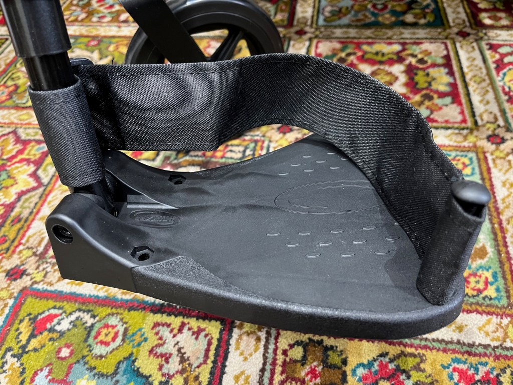 A black footrest attached to a wheelchair.