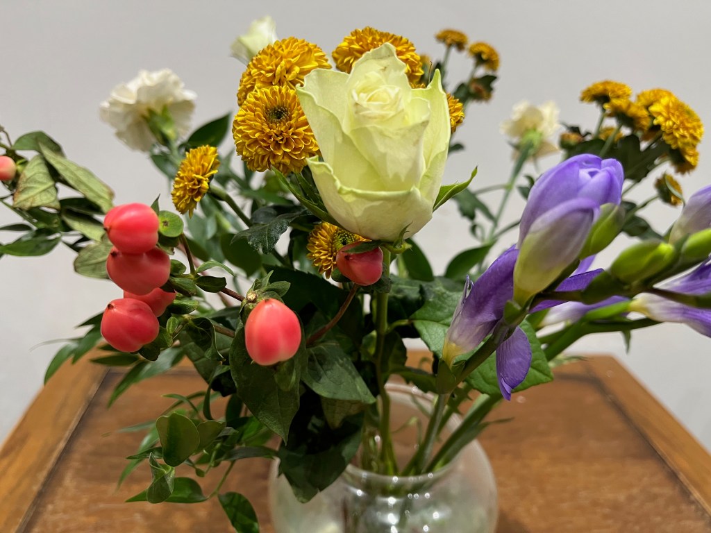 Close-up of some colourful flowers in a vase, some of which are still in bud and haven't fully opened yet.