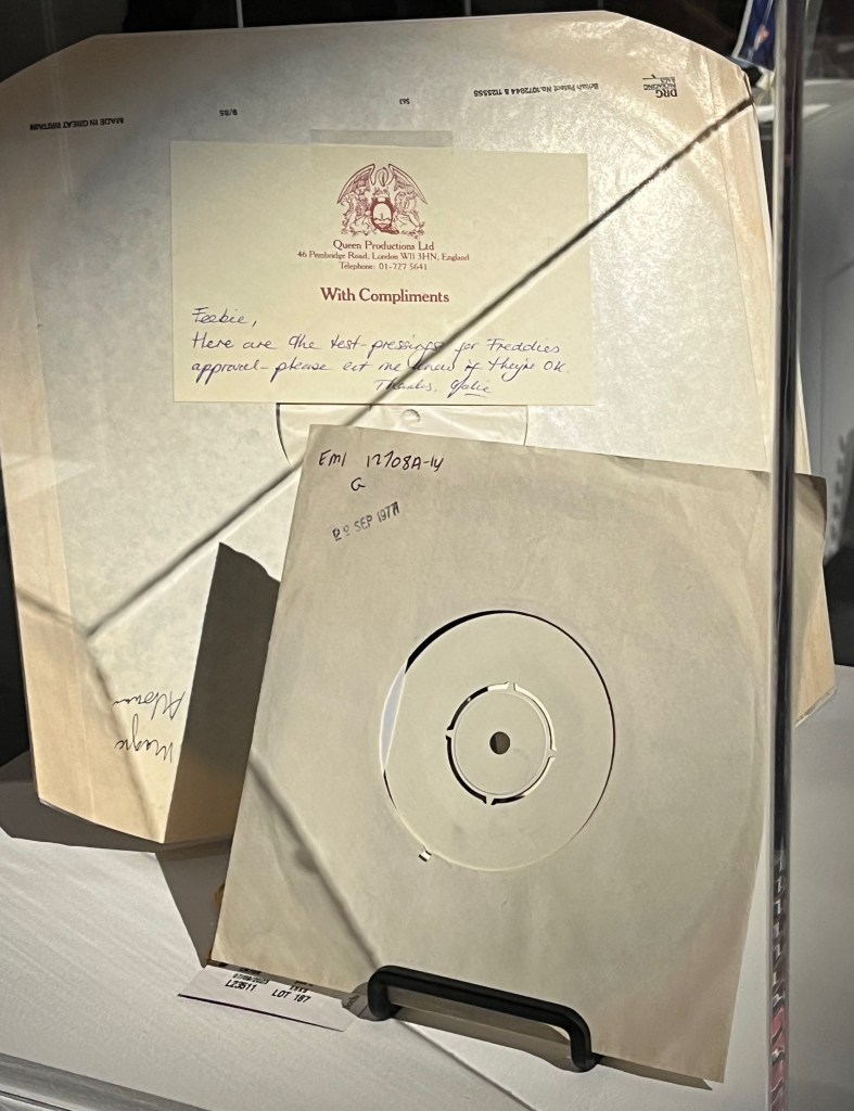 A 12-inch vinyl test pressing of A Kind Of Magic, by Queen, in a white sleeve. It comes with a headed paper compliments slip with a handwritten message that reads Feebie, Here are the test-pressings for Freddie's approval - please let me know if they're ok. Thanks, Julie.