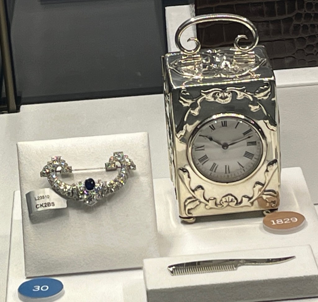 A sapphire and diamond brooch, and a silver Victorian clock decorated with small cherubs and foliage.