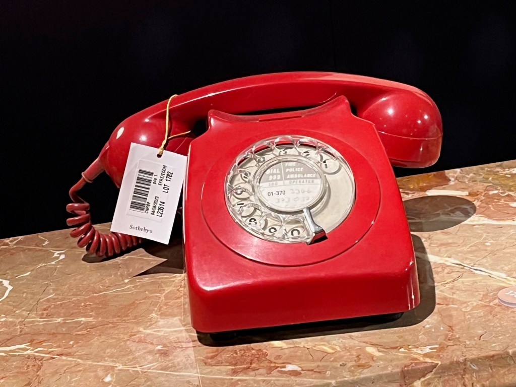 A red telephone with a white rotary dial.