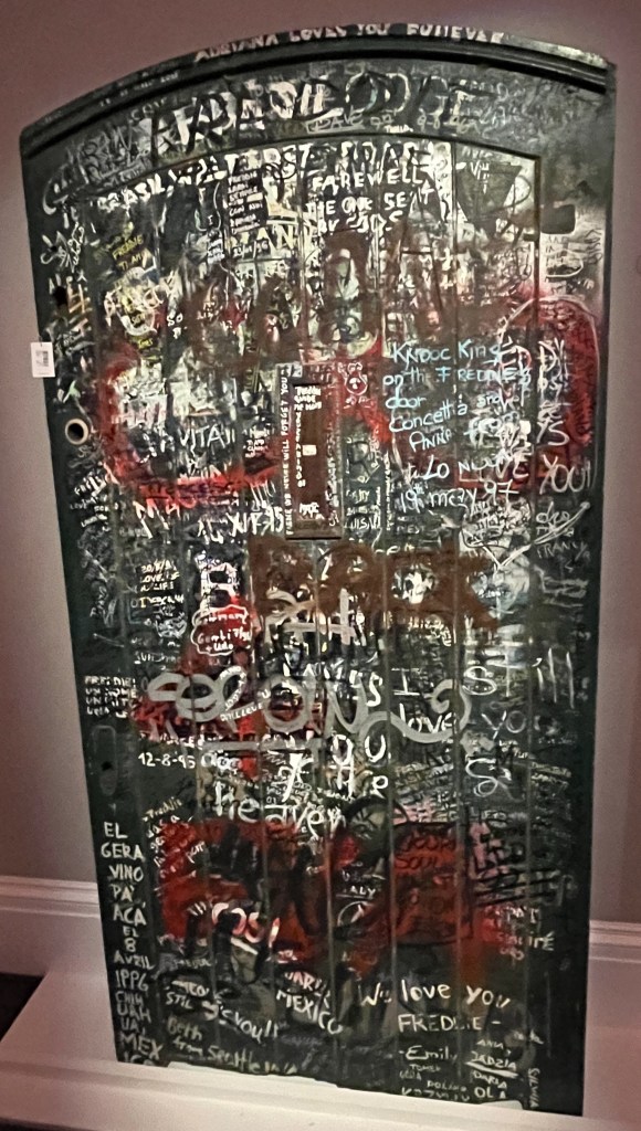 The large green door to Garden Lodge, viewed straight on, covered in graffiti from fans in tribute to Freddie Mercury.