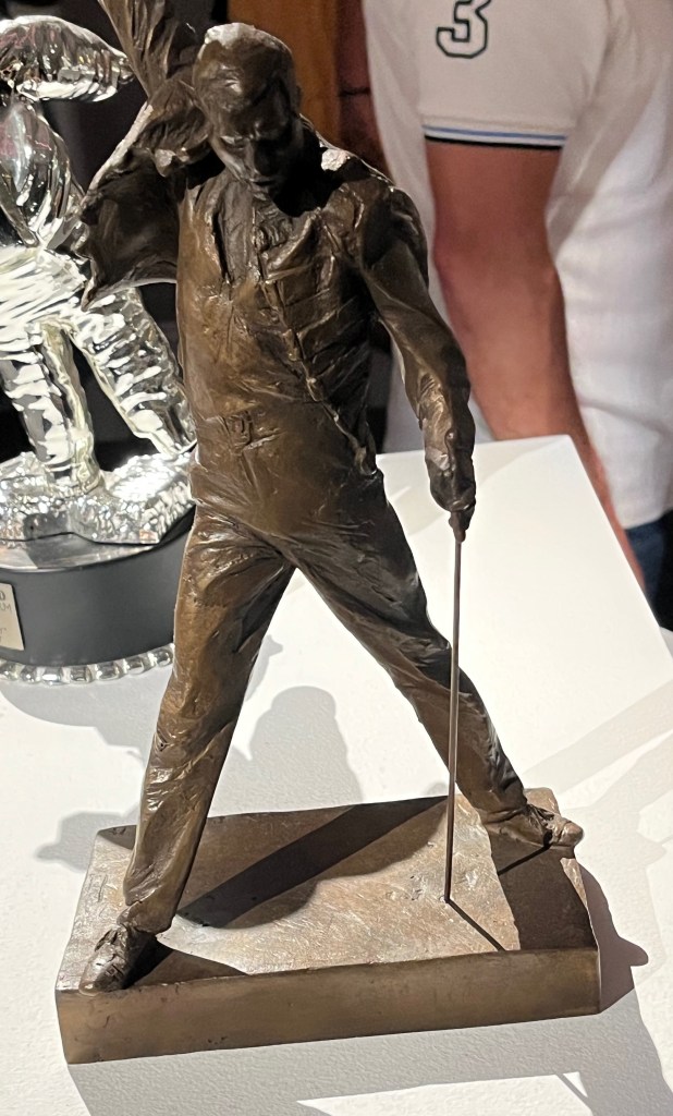 A bronze statuette of Freddie Mercury posing with legs outstretched and one arm pumping the air above him.