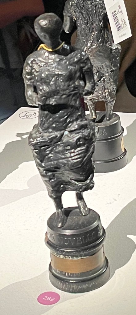 An Ivor Novello award, consisting of a bronze statuette of Greek muse Euterpe on a circular black wooden plinth.