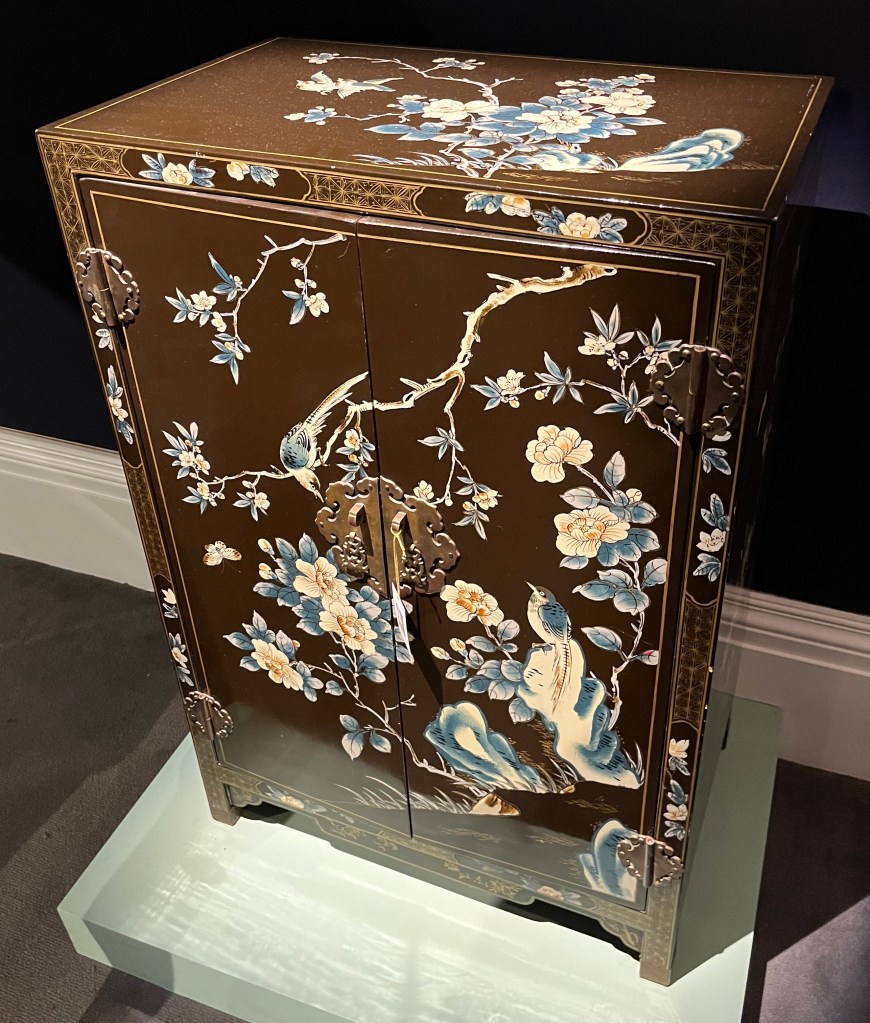 A cabinet with painted decorations of flowering branches and birds.