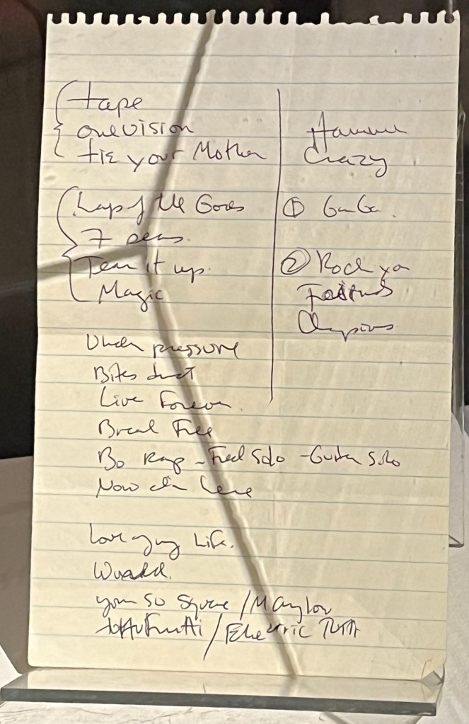 Freddie Mercury's handwritten set list during the Magic tour, with song names often abbreviated, including One Vision, Tie Your Mother, Lap Of The Gods, Tear It Up, Magic, Under Pressure, Bites Dust, Live Forever, Break Free, Bo Rhap with Fred solo and guitar solo, Now I'm Here, Love Of My Life, You're So Square, Tutti Frutti, Crazy, Ga Ga, Rock You, Friends and Champions.