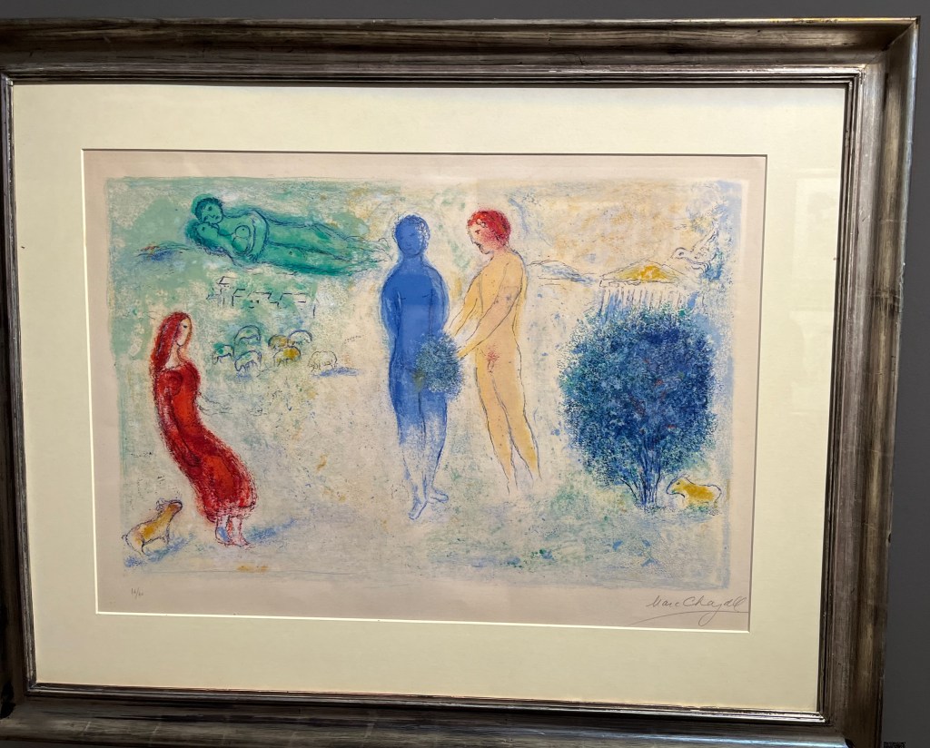 Painting by Marc Chagall called Chloe's Judgement. It depicts a naked couple, with the woman in blue while the main is a more normal skin colour, standing together, the man holding some foliage from a nearby tree over the lady's groin area. A woman dressed in red sites and watches them from the side.