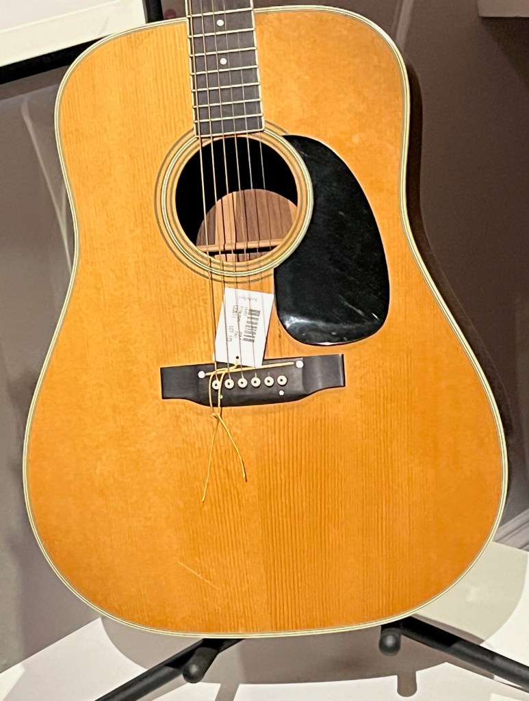 A Martin D-35 Acoustic Guitar, in a natural light wood colour, with a black section to the right of the sound hole..