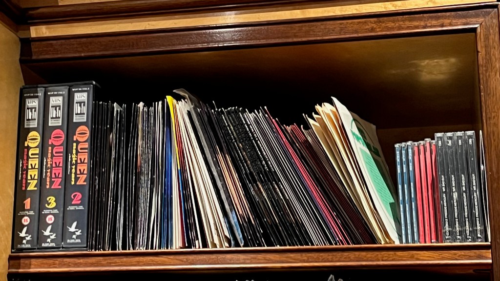 A selection of Queen & Freddie Mercury records from Freddie's record collection, alongside 3 volumes of the VHS video series called Queen The Magic Years.