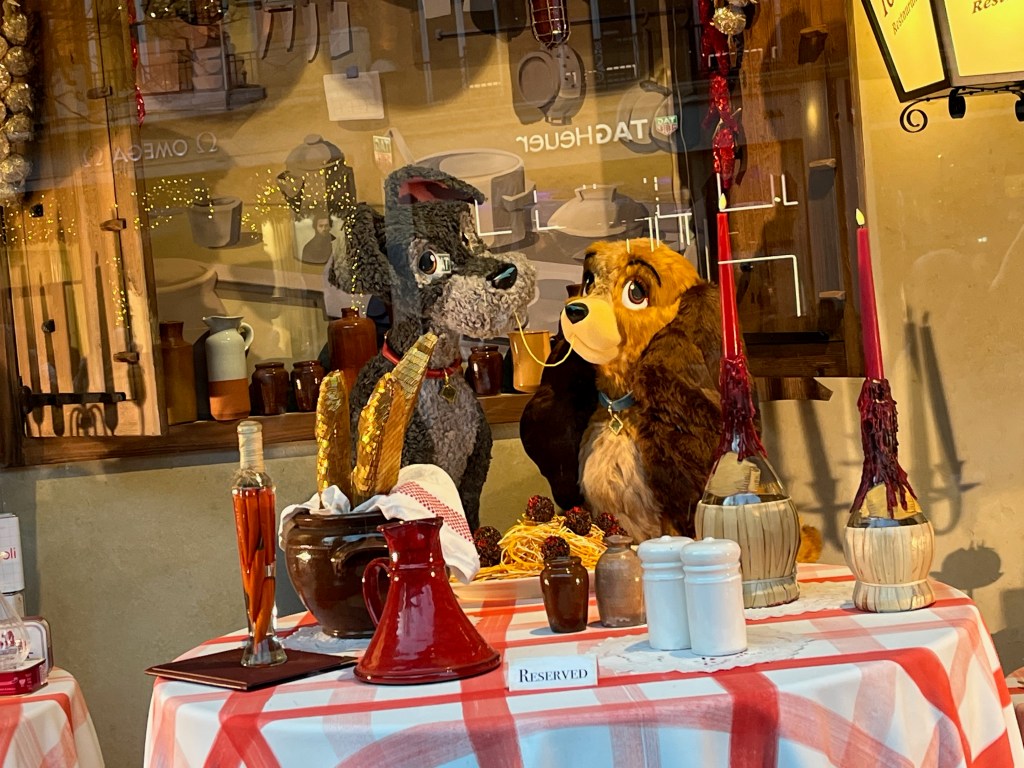 Close-up of two dogs at a restaurant table, sharing a strand of spaghetti between them, in a Selfridges window display representing Lady And The Tramp.