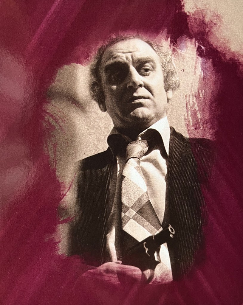 A black and white photo of Regan wearing a jacket, shirt and tie, looking down at us. The image is placed on a red background, and is from one of the panels in the Blu-ray box set for The Sweeney Series 3.