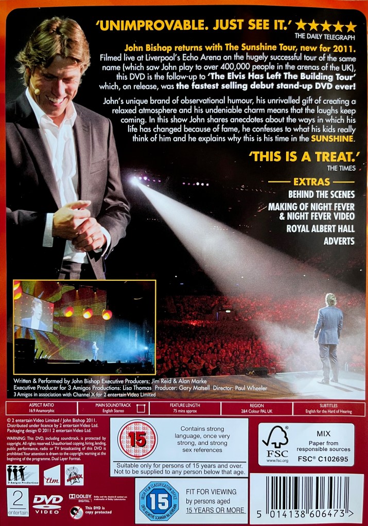 Back cover of John Bishop's DVD called Sunshine. It shows a few images of John performing on stage, including one with a large spotlight pointing at him, alongside the description of the show and the list of extra features.