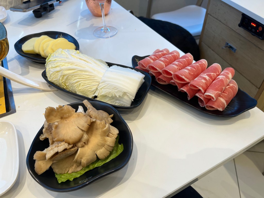 A selection of side dishes including slices of lamb, potato, cabbage and mushrooms.
