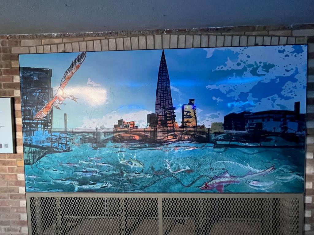 A painting of a bird with an orange tint to its wings diving down towards fish swimming in the River Thames, with the Shard prominent in the background on the opposite bank.
