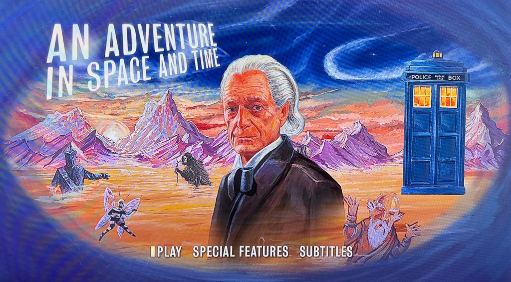 The main menu on the Blu-ray for the Doctor Who biographical drama An Adventure In Space And Time. It shows a painting of the first Doctor on a desolate planet with mountains in the background beneath a blue starry sky. There are some alien characters scattered around the landscape, and the Tardis is parked on the right. The title of the drama is in large capital letters at the top of the image. Across the bottom are the menu options Play, Special Features and Subtitles.