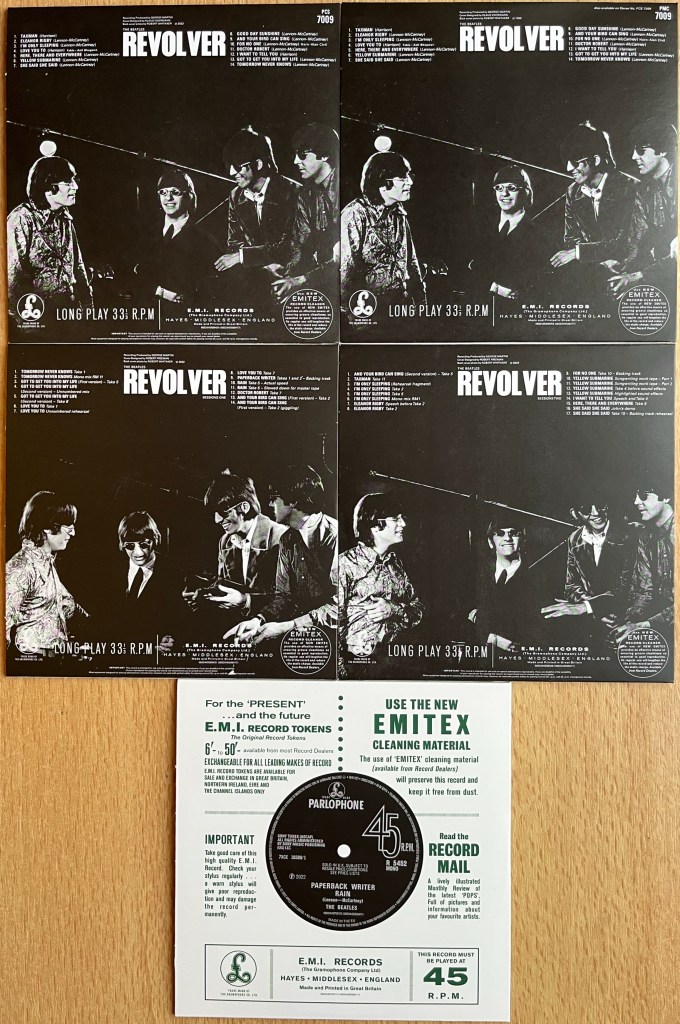 The back covers of the 5 cardboard sleeves for the CDs in the Revolver box set. 4 of the cases have a black background with the tracklisting in white text at the top, and a black and white photo of the band below. The photos on the first 2 covers are the same, but those on the other two discs are different, though clearly from the same photoshoot, as the band members are just posing slightly differently. The back cover of the final disc looks like the back of an old vinyl EP case, with the record showing through the big hole in the centre.
