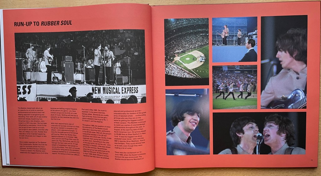 Double-page spread from the large hardback book with the box set for the Beatles album Rubber Soul. Both pages have a red background. The left page has the heading Run-Up To Rubber Soul at the top left. Below that is a black and white photo of the band performing on the stage, on the front of which is a banner advertising the New Musical Express. Below the image are 4 columns of black text. The right page has a collage of 6 colour photos of the band performing. One has an aerial view of the band in a baseball stadium. The next one shows a side view of the band on a stage in a stadium. Another shows them walking across grass in a stadium. The other 3 photos are then close-up headshots of the band members playing or singing.