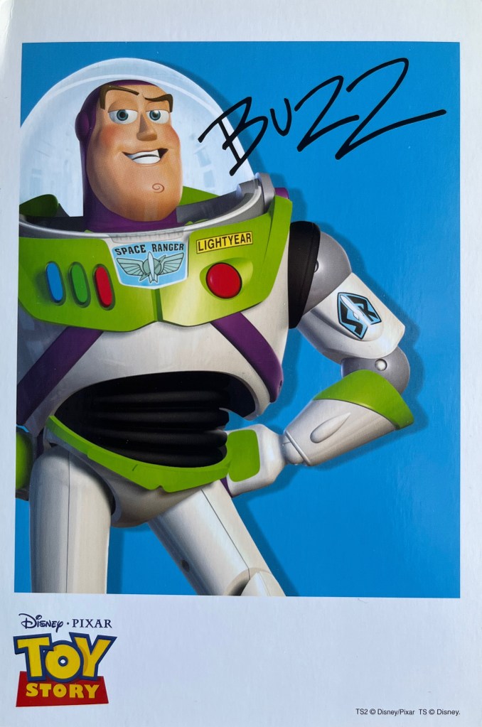 A Toy Story art card showing Space Ranger Buzz Lightyear standing against a blue background, with his signature in black next to him.