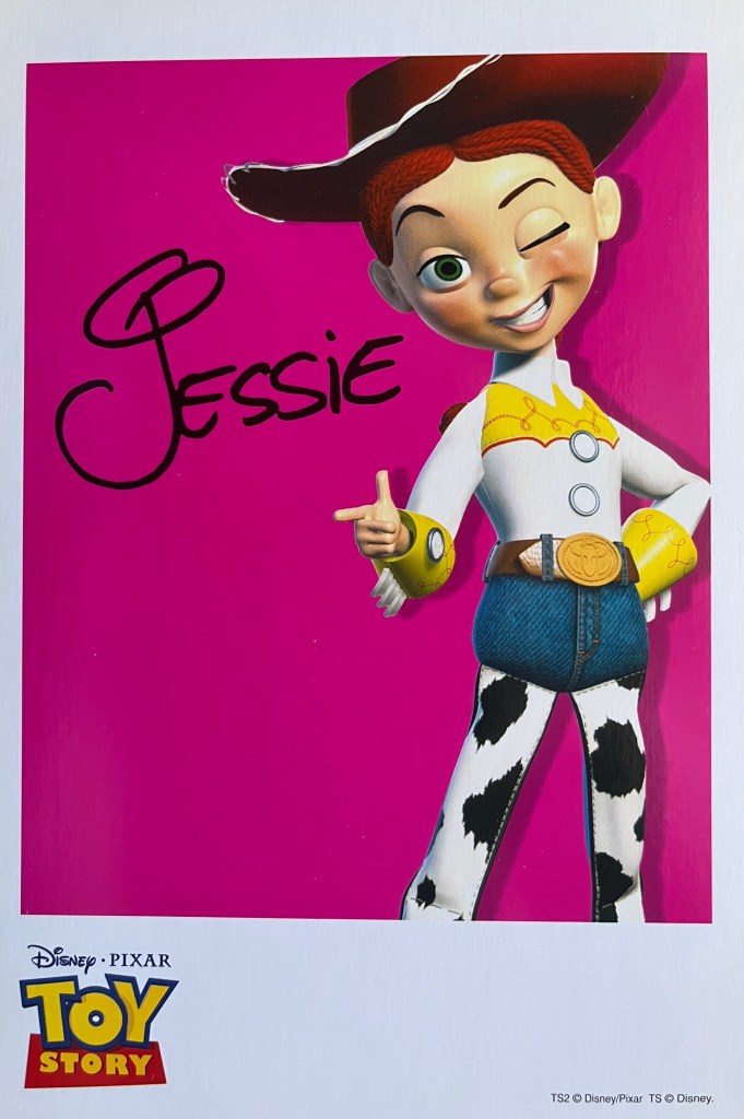 A Toy Story art card showing cowgirl Jessie standing against a pink background, with her signature in black next to her.